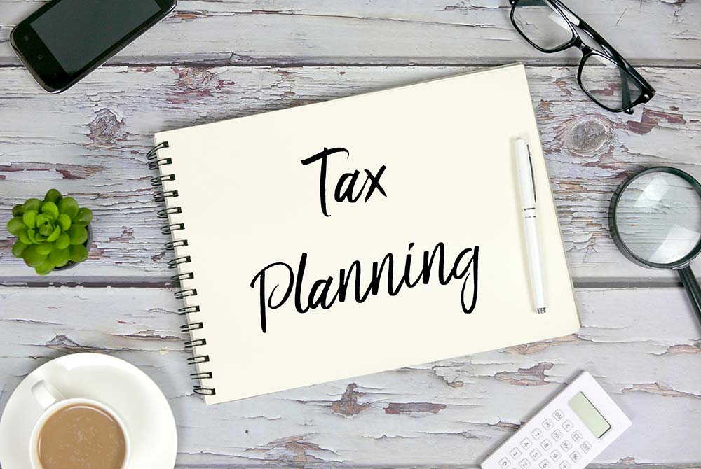 table top with coffee, house plan and scratch pad with "Tax Planning" written on it